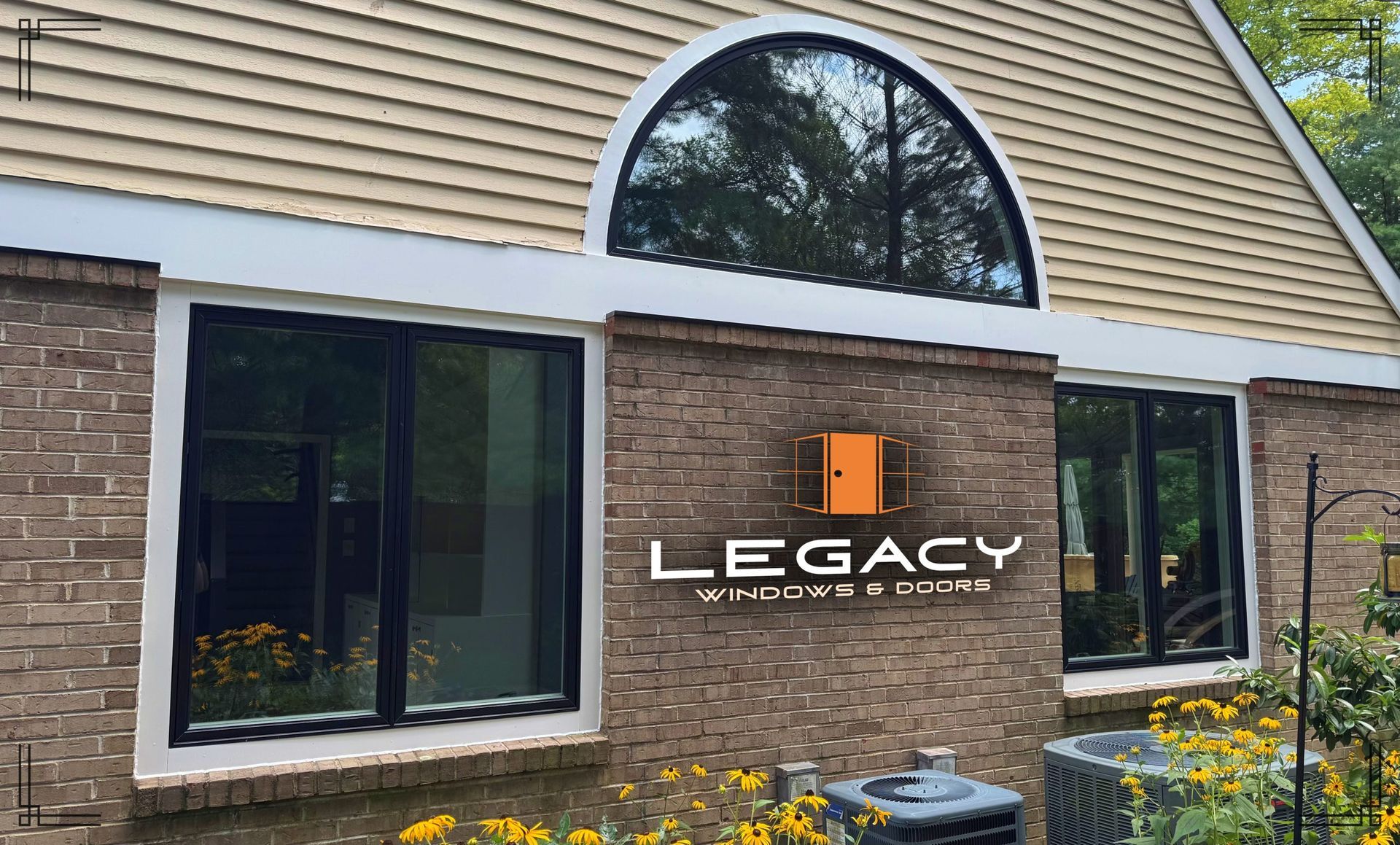 Exterior view of a brick home with black-framed windows, a large arched window, and