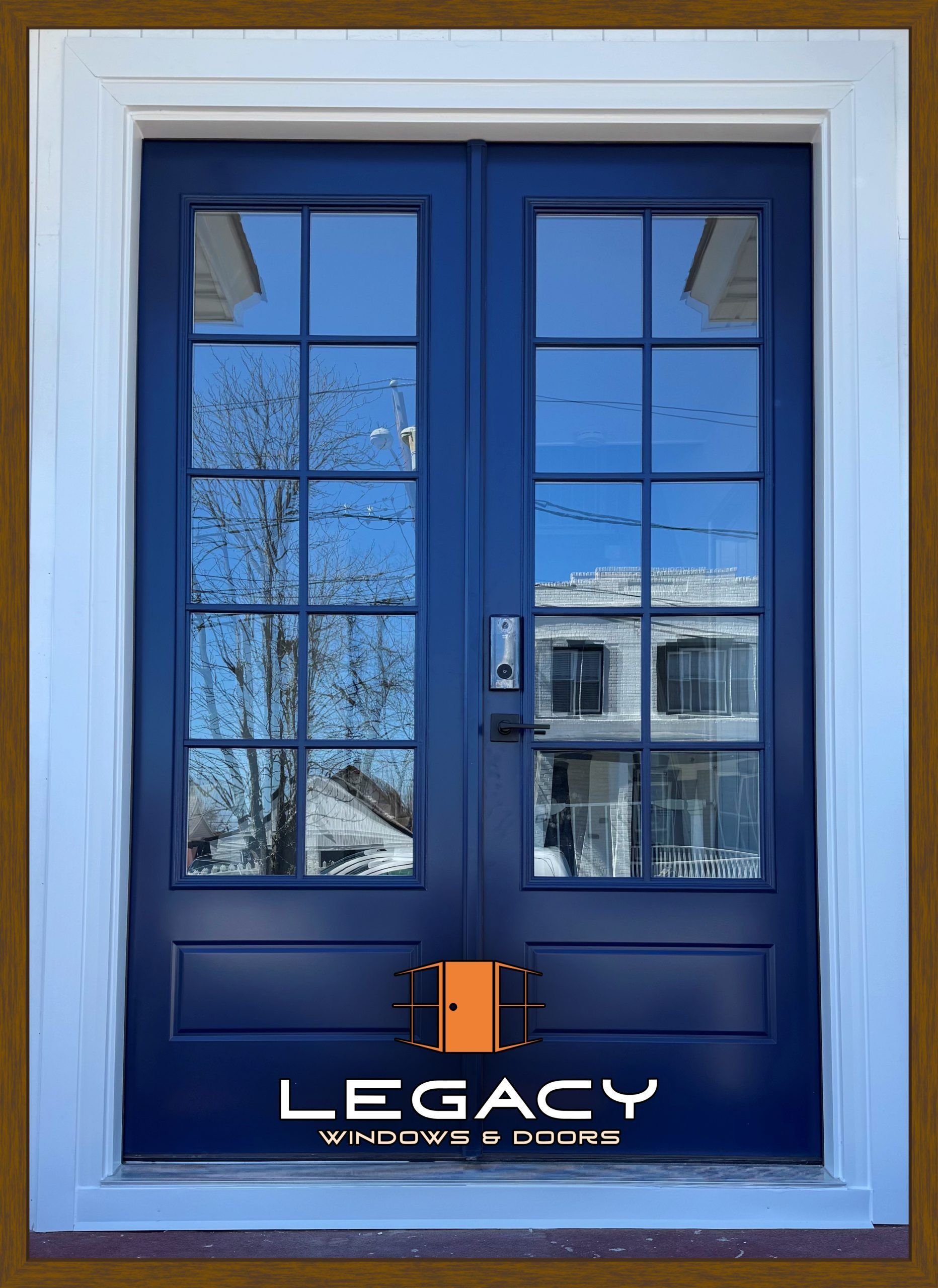 Blue double doors with glass panels reflecting a building and trees, set in a white frame. Legacy logo at the bottom.