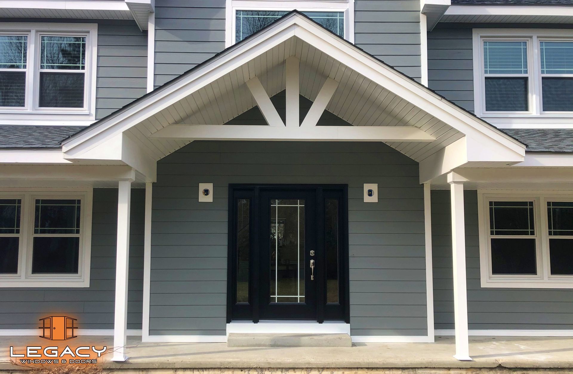 Gray house exterior with white trim, covered entryway, and black front door.