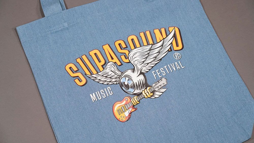 A Blue Tote Bag With a Picture of an Eagle and a Guitar on It — Carnival Clothing In Miami, QLD