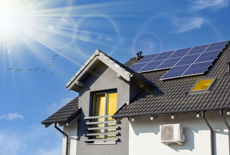 House roof with solar panels under a bright blue sky and sun rays