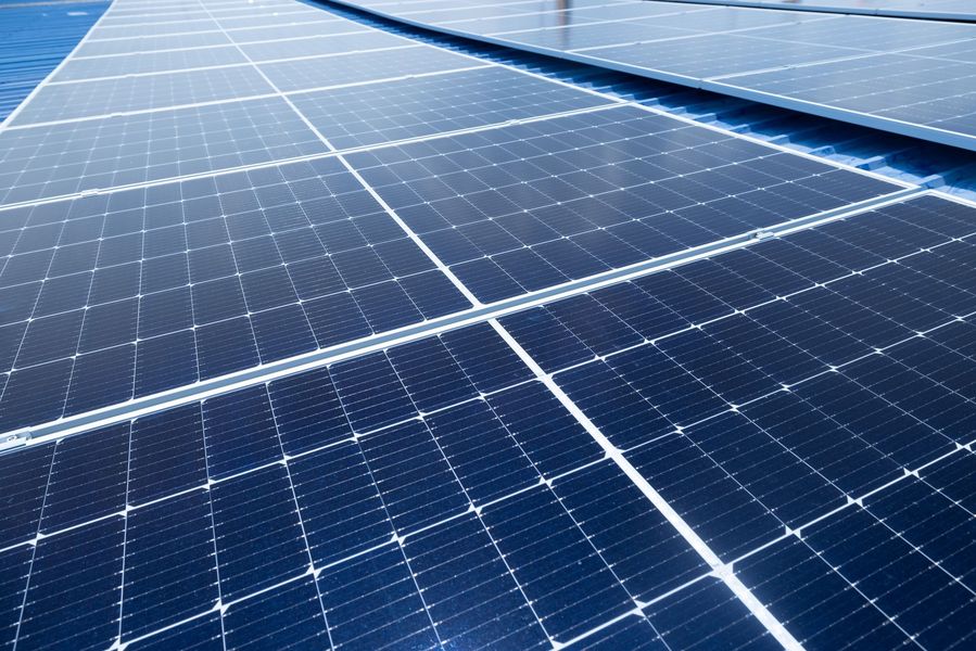 Rows of blue solar panels under a clear sky, angled across a rooftop