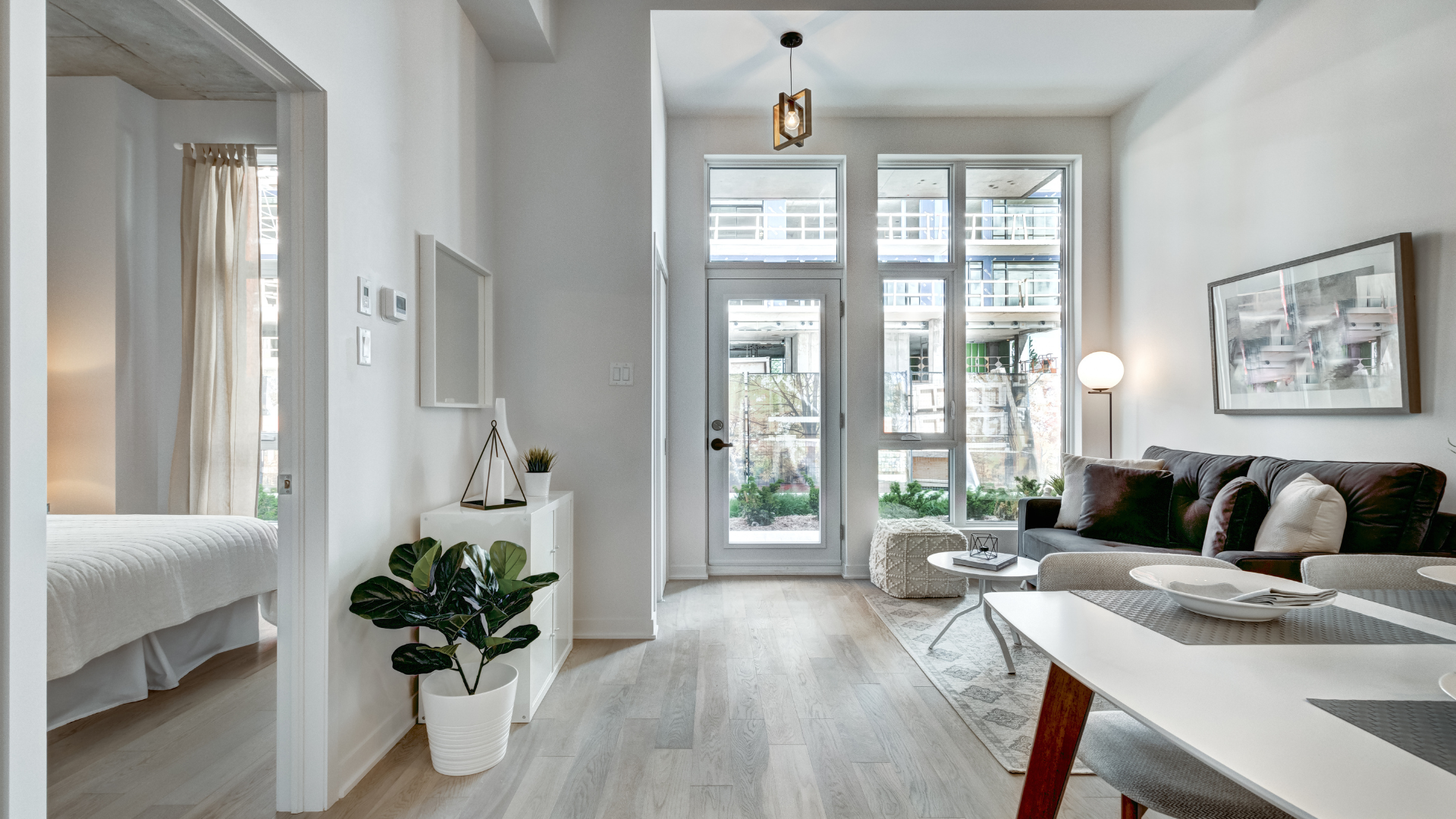 Modern apartment interior with white walls, large windows, and a sofa.