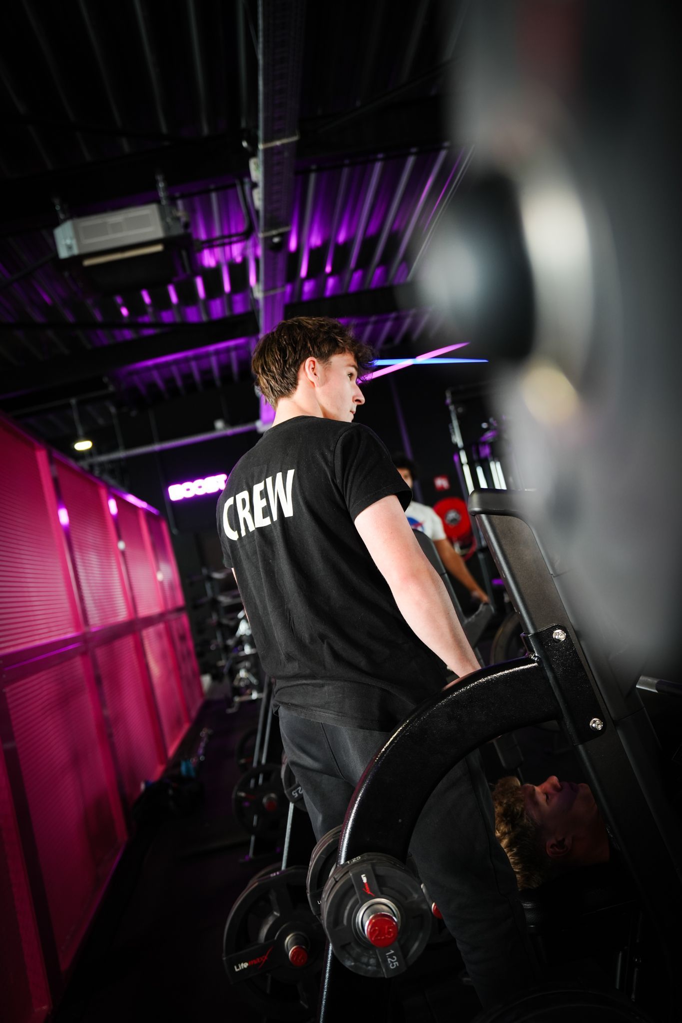 Een sportschool met veel fitnessapparatuur en een houten vloer.