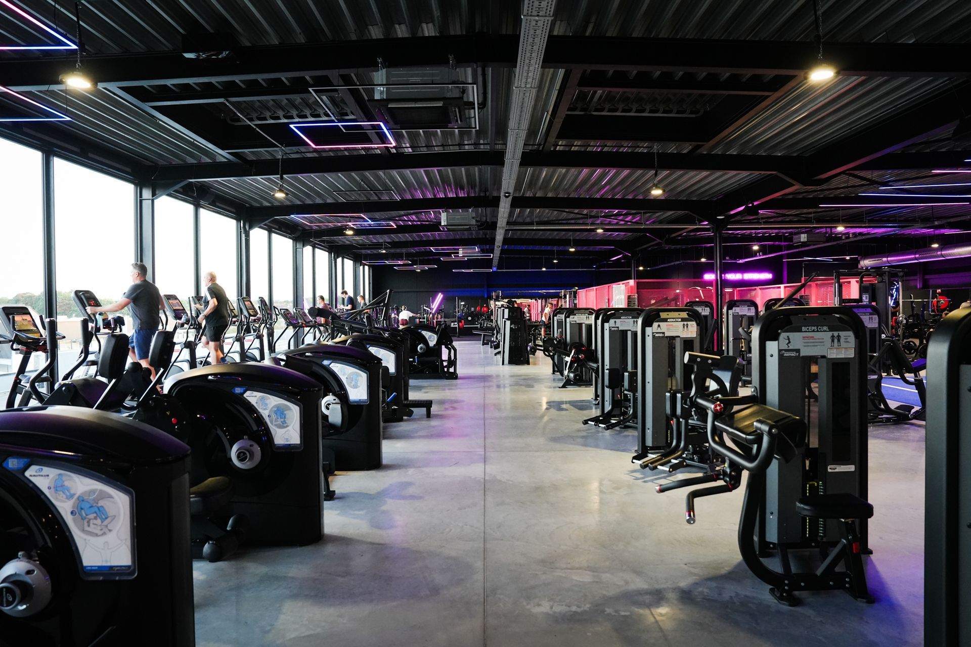 Een sportschool vol met fitnessapparatuur en een blauwe mat.