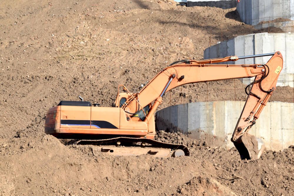 A Large Excavator Is Digging A Hole In The Dirt Ground — Dicko's Bobcat & Tipper in East Bendigo, VIC