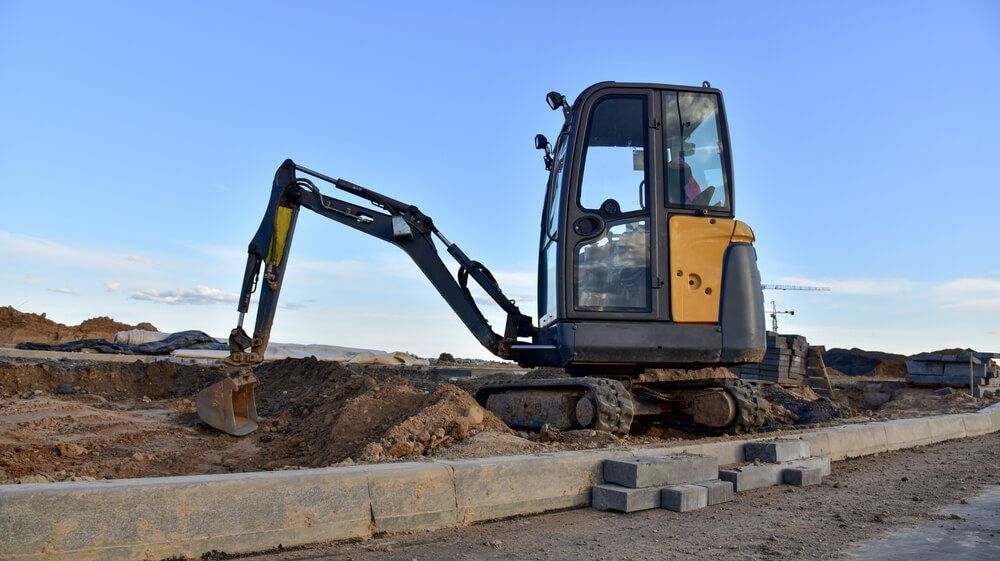 A Small Excavator Is Working On A Construction Site — Dicko's Bobcat & Tipper in East Bendigo, VIC