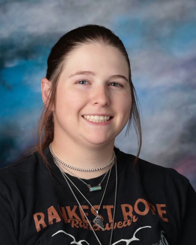 A woman is smiling for a picture in front of a blue background.