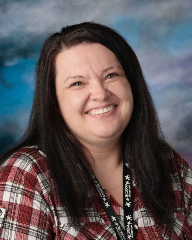 A woman wearing a black shirt with a rainbow on it is smiling for the camera.
