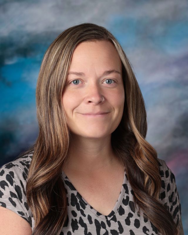 A woman is posing for a picture in front of a blue background.