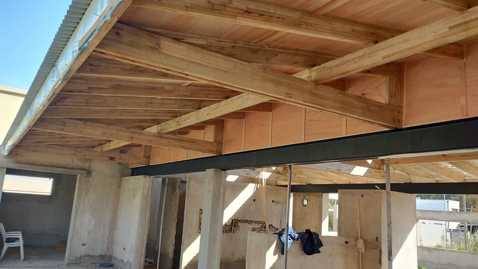Vigas de madera y estructura de construcción a la vista en el interior de un edificio sin terminar.