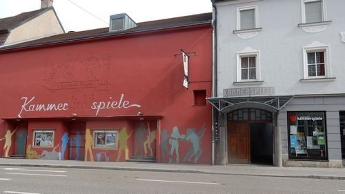 Kammerspiele Ansbach. Langgestrecktes  ehem. Kinogebäude mit angrenzendem mehrgeschossigem historischen Gebäude  mit Torbogen.