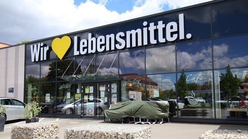 Cafe Greller neben Edeka. Modernes Gebäude mit Glasfassade.