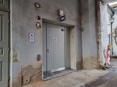 Eingang WC Reitbahn Graue Tür in grauer Mauer