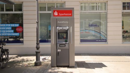 Geldautomat mit der Aufschrift Sparkasse vor einem Haus.