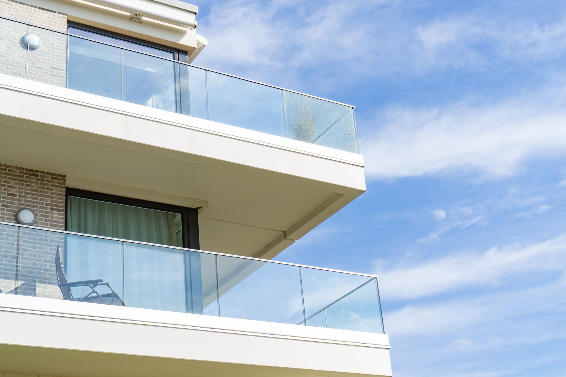 Modern apartment balconies with glass railings against a blue sky