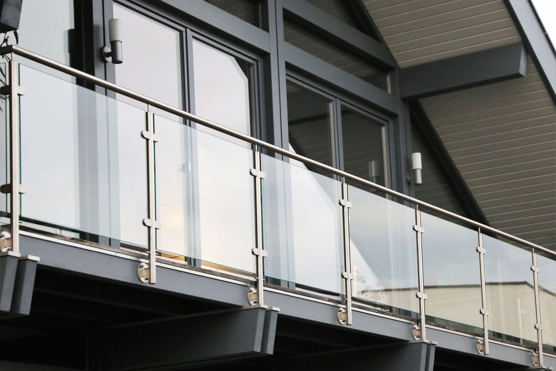 Modern building balcony with glass railings and gray siding