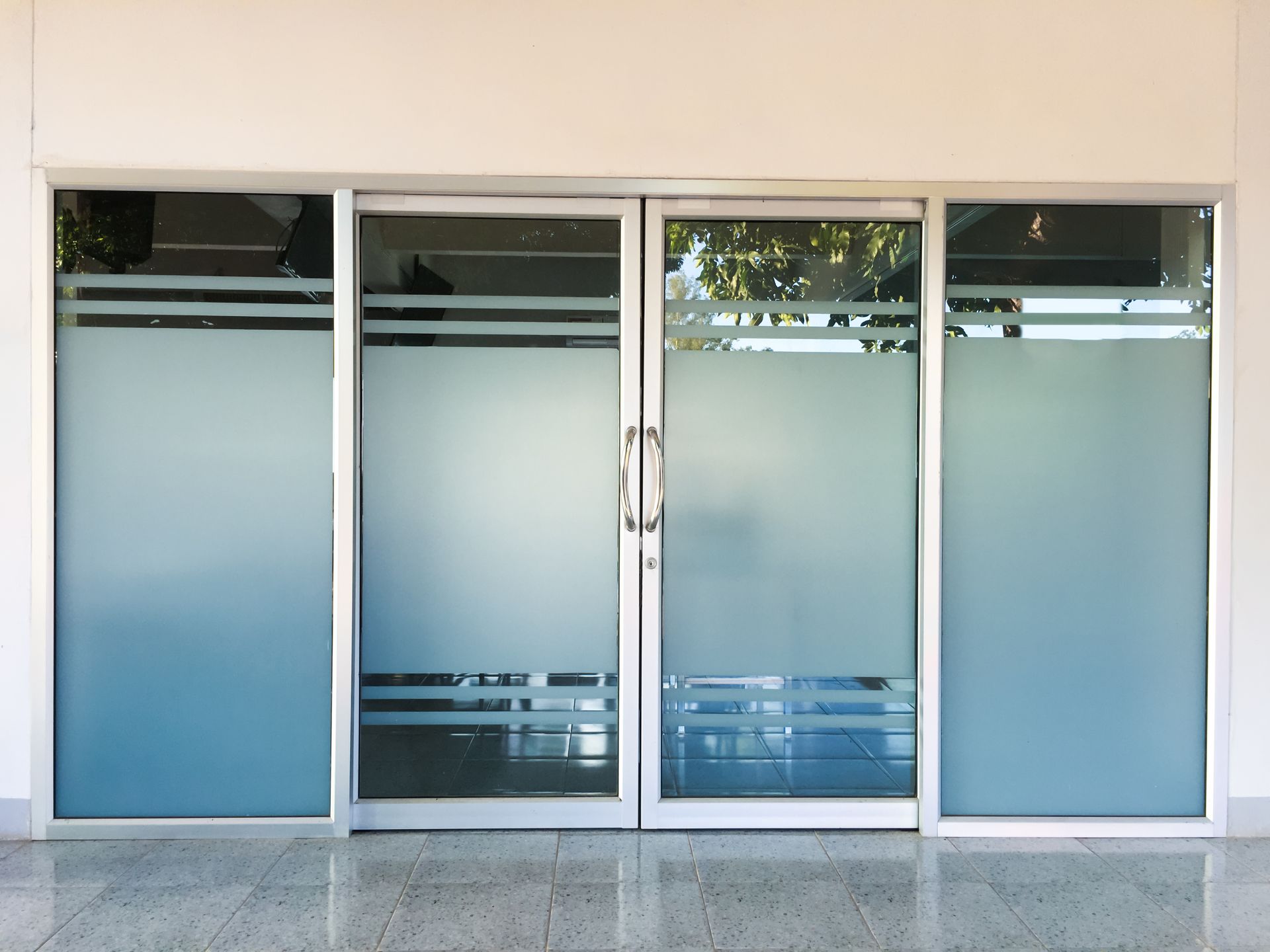 Modern glass-fronted building with slanted facade and reflective windows under a clear blue sky Modern glass-fronted building with slanted facade and reflective windows under a clear blue sky