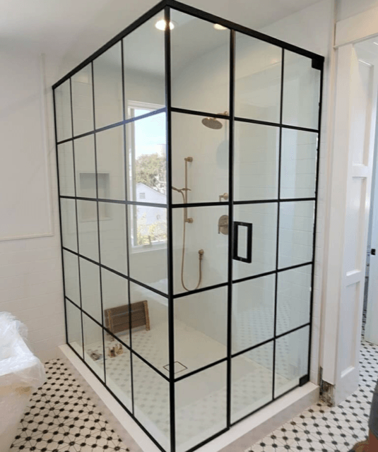 Black-framed glass shower enclosure in a bright tiled bathroom