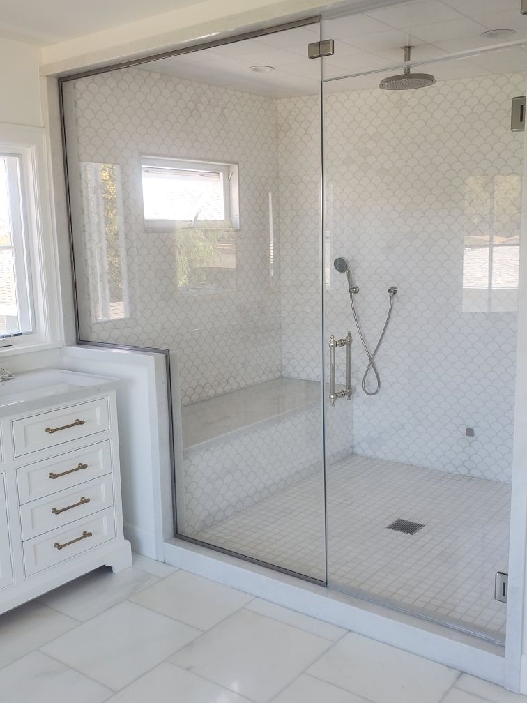 Modern white bathroom with glass-enclosed walk-in shower and tiled floor