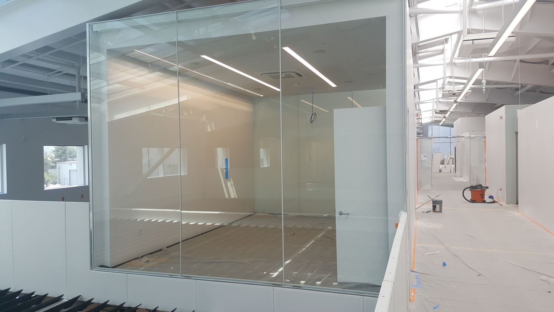 Empty modern office with glass-walled room and construction materials in a bright unfinished space Empty modern office with glass-walled room and construction materials in a bright unfinished space