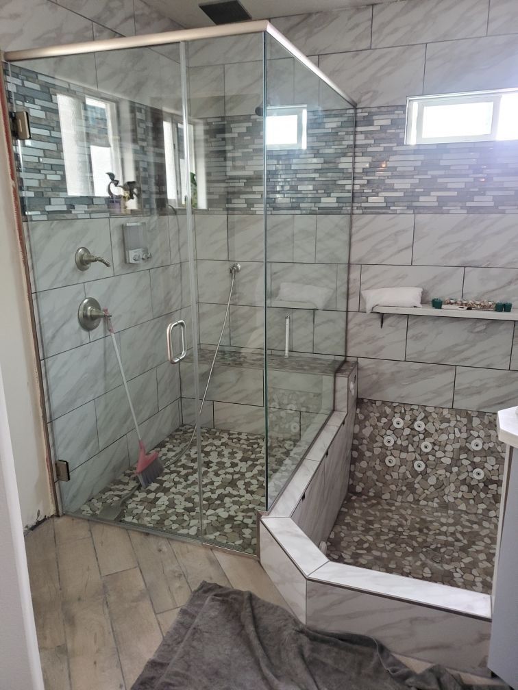 Bathroom with glass walk-in shower, tiled walls, and mosaic-tile floor beside a raised toilet area.