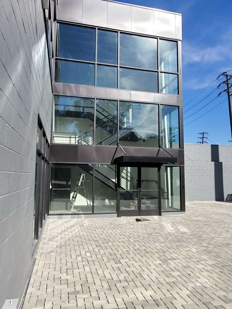 Modern glass-fronted building with slanted facade and reflective windows under a clear blue sky