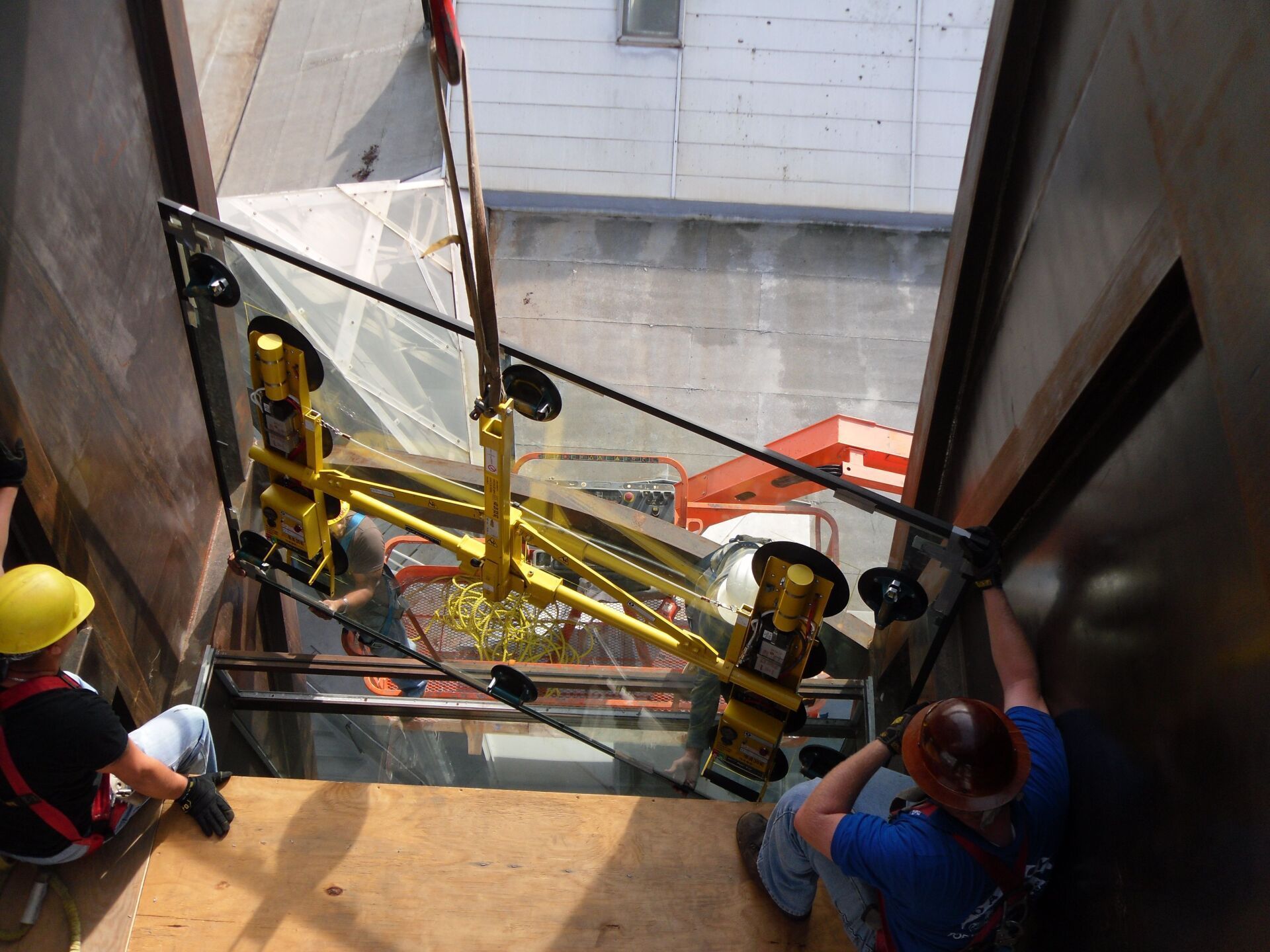 Workers lowering a yellow construction lift into a narrow building shaft Workers lowering a yellow construction lift into a narrow building shaft