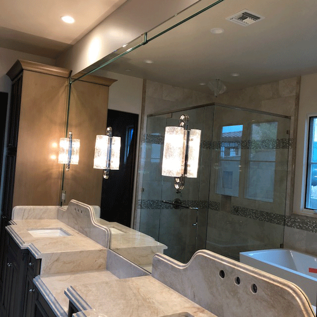 Modern bathroom with double sinks, large mirror, wall sconces, and glass-enclosed shower. Modern bathroom with double sinks, large mirror, wall sconces, and glass-enclosed shower.