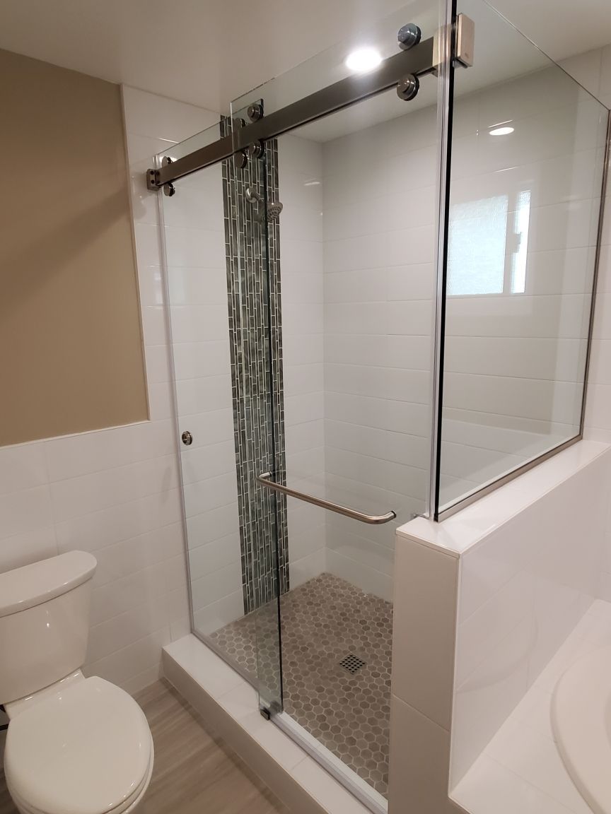 Bathroom with glass walk-in shower, pebble floor, and toilet beside it