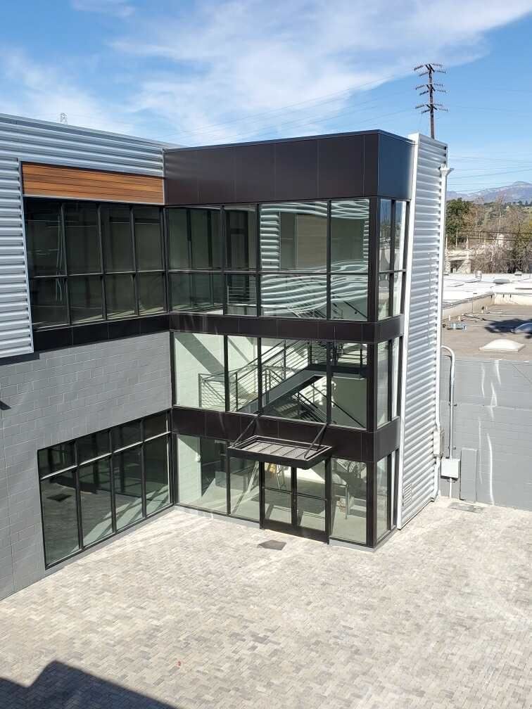 Modern glass-and-metal building with two-story windows and an exterior staircase Modern glass-and-metal building with two-story windows and an exterior staircase