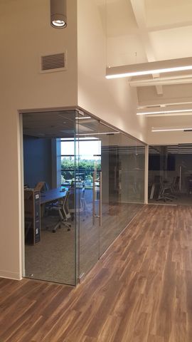 Modern office interior with glass-walled meeting rooms and wood-look flooring