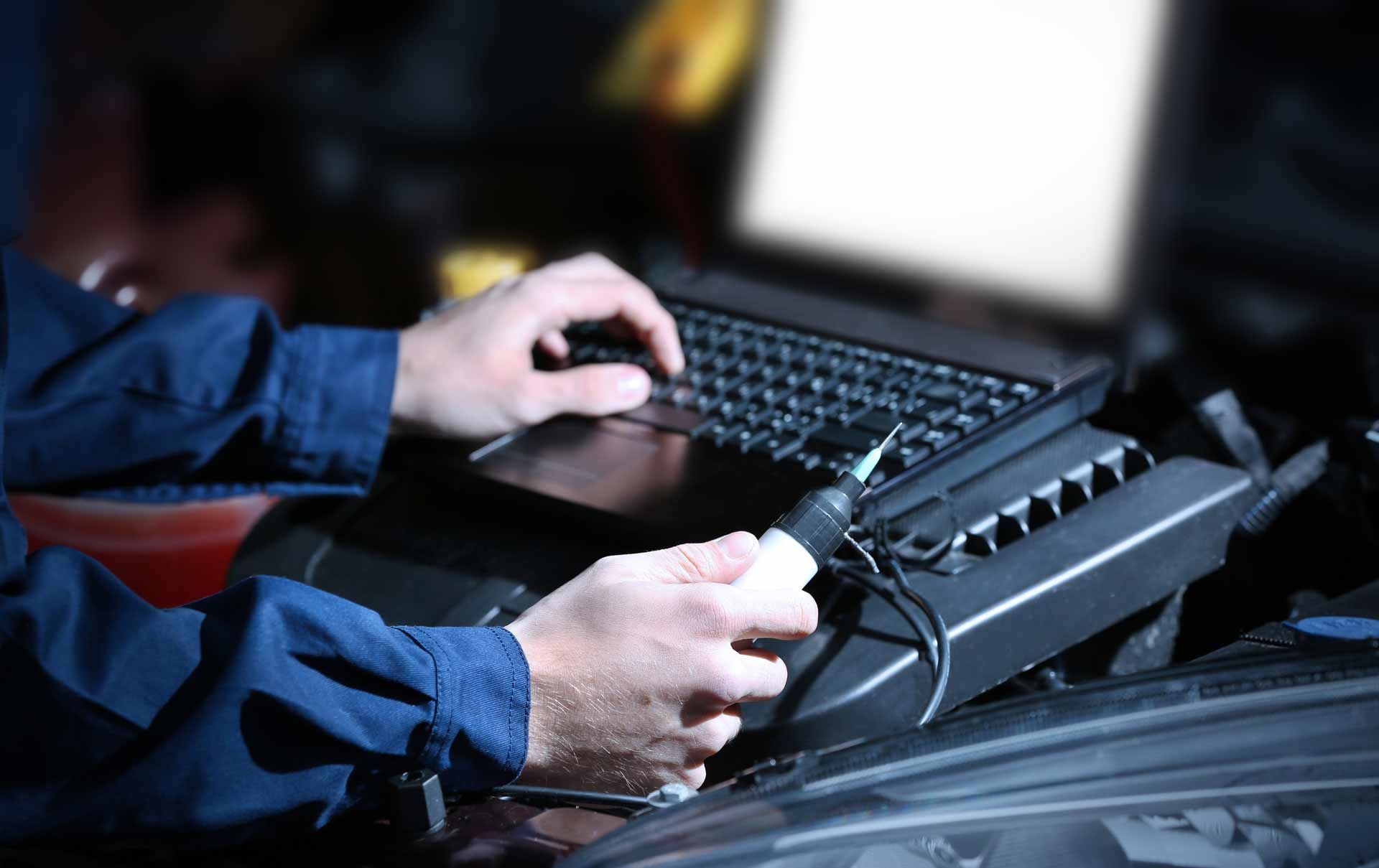 Hands typing on a laptop keyboard beside a radio transceiver in a dim room
