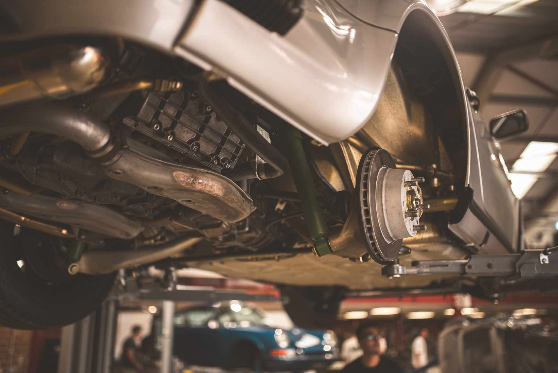 Underside of a car on a lift, showing exhaust and suspension in a garage