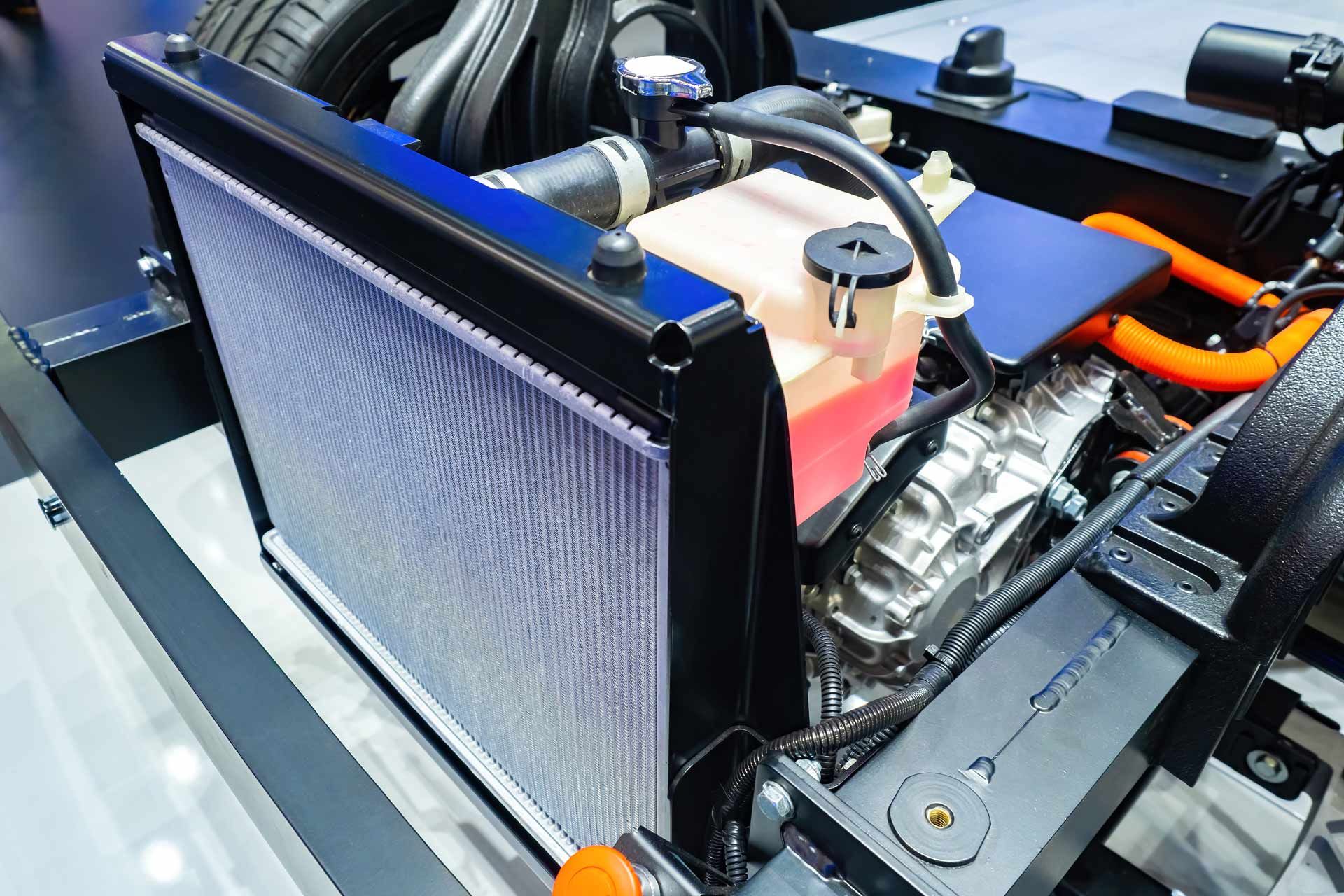 Close-up of a car engine bay with a blue radiator and visible hoses and wiring