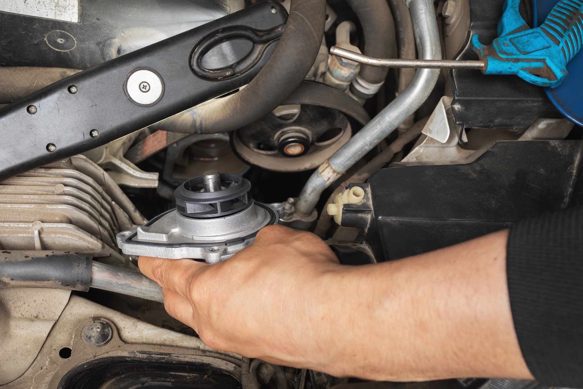 Hand tightening a car engine part under the hood with a wrench.