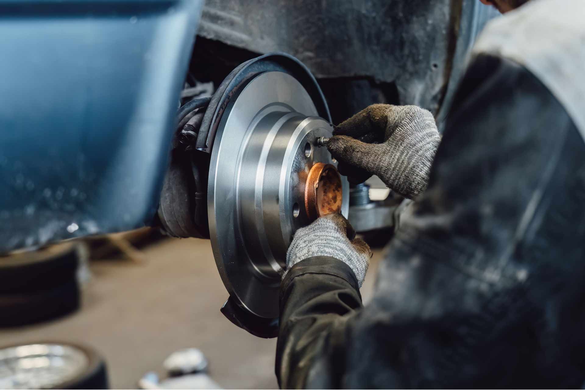 Mechanic polishing a car brake rotor with a grinding tool in a garage