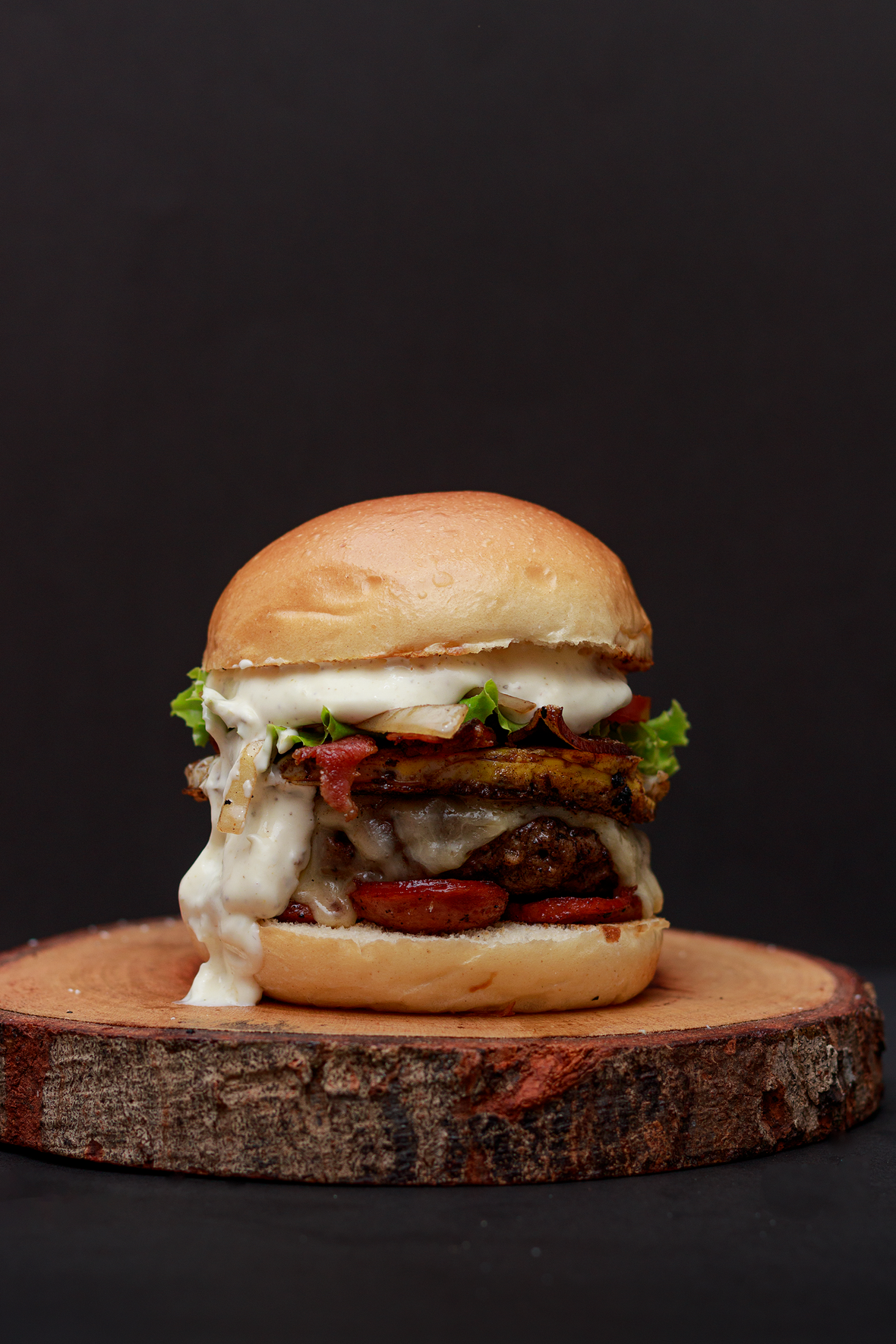 Hamburger con formaggio fuso su un tagliere di legno su sfondo scuro