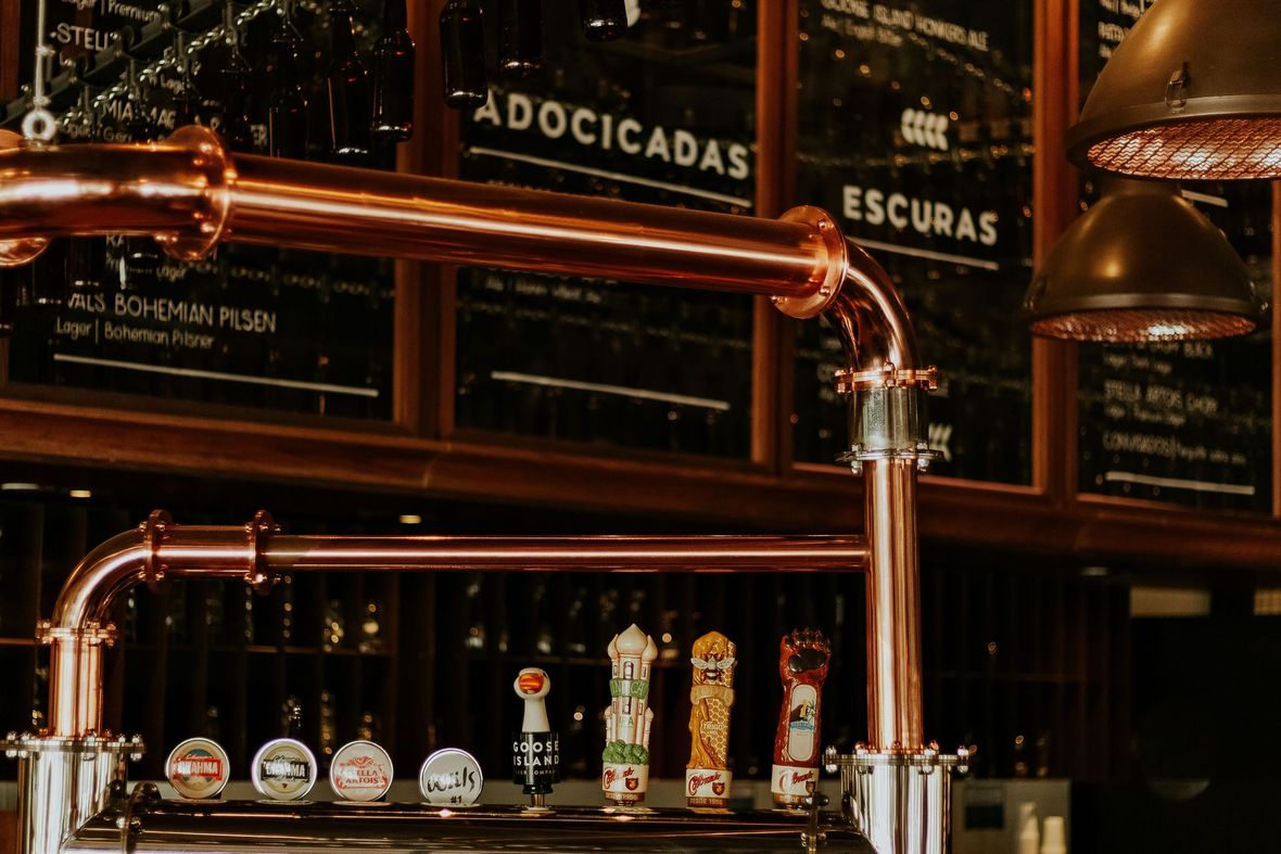 Rubinetti della birra in rame e tubi in ottone in un bar scarsamente illuminato