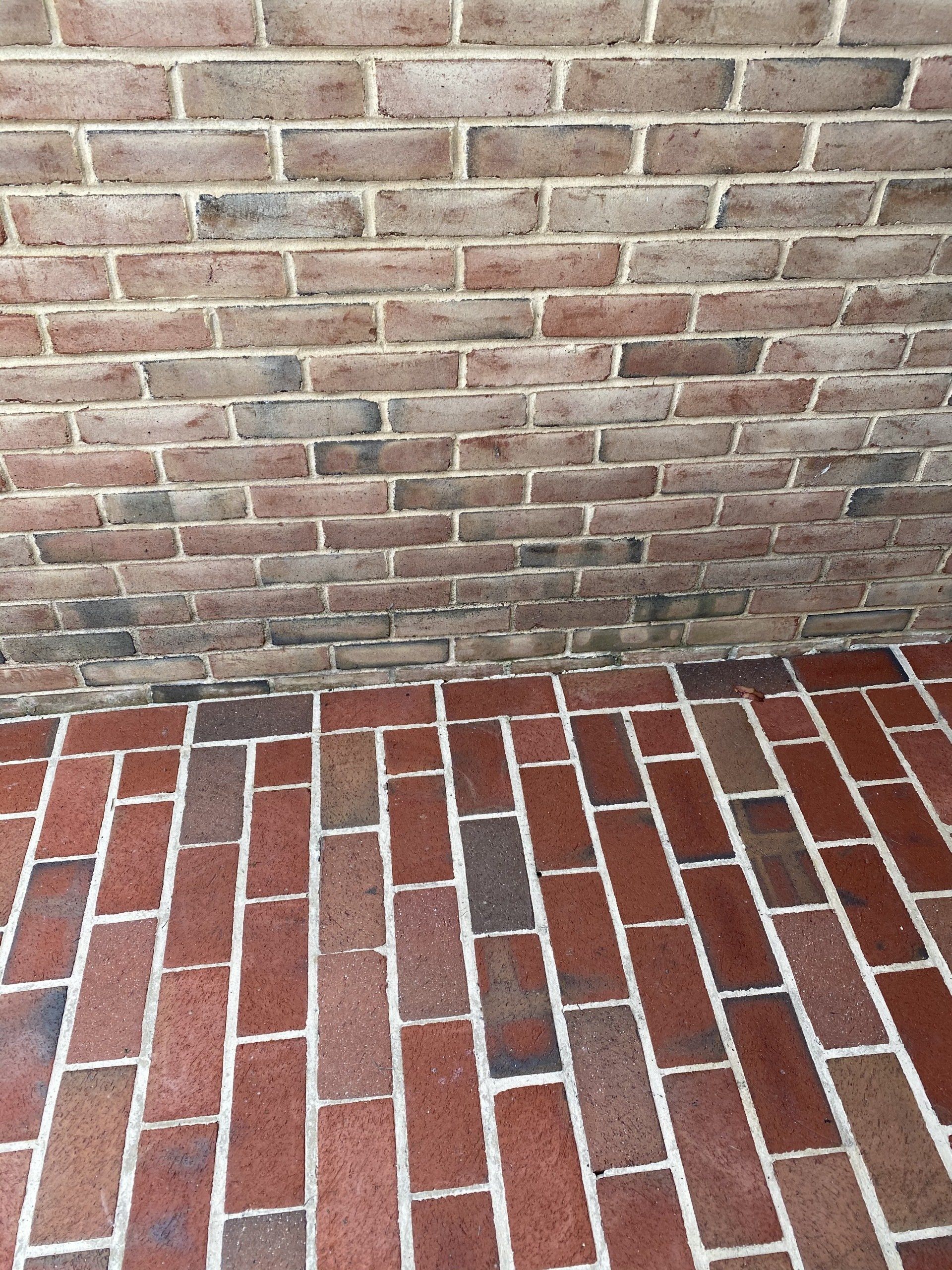 Red brick walkway meeting a weathered red-brick wall, with gray mortar lines.