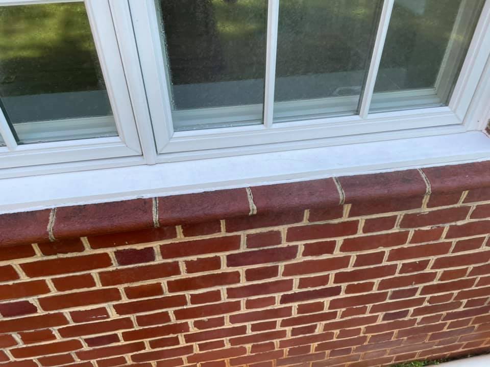 Brick exterior wall below a white-framed window with a red sill