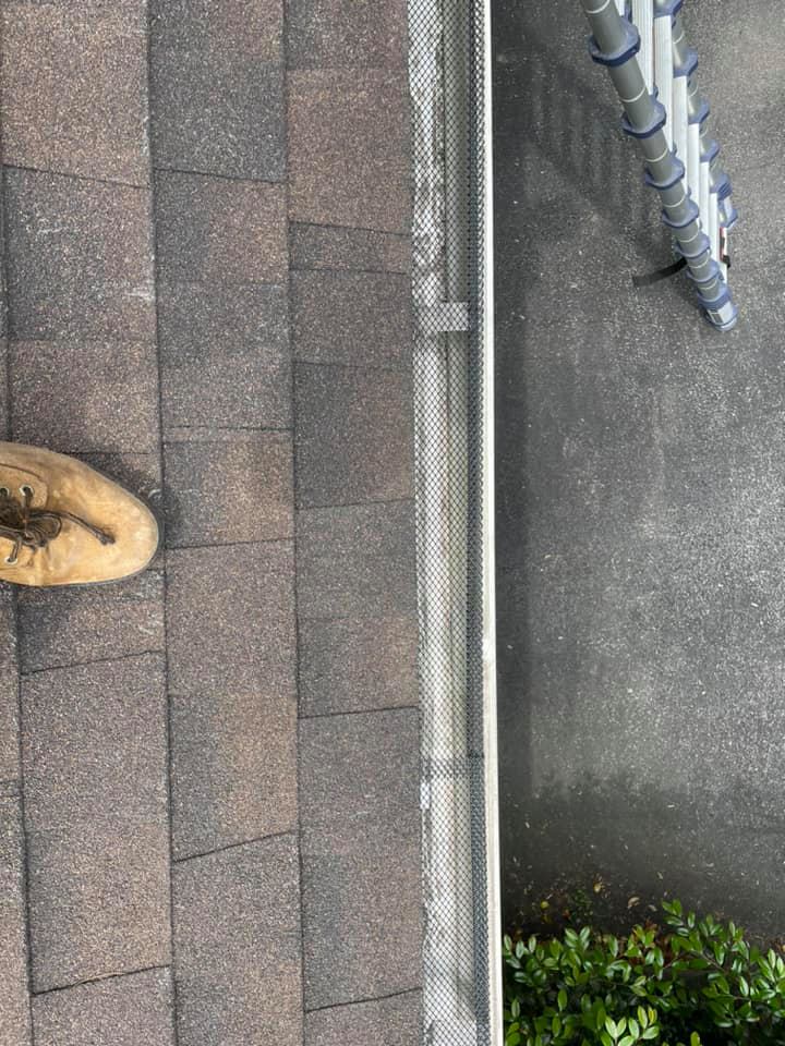 Rooftop view with shingles, a gutter edge, and a tan boot at the lower left.