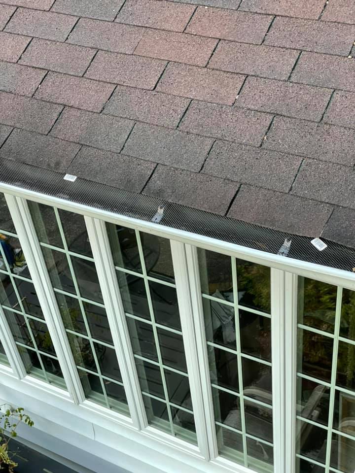 Exterior of a house with white-framed windows beneath a brown shingle roof, viewed from above