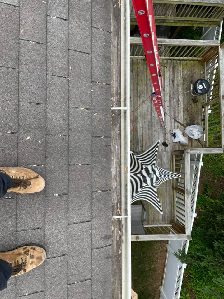 Person standing on a rooftop near a red ladder and a black-and-white umbrella by a stairwell opening.