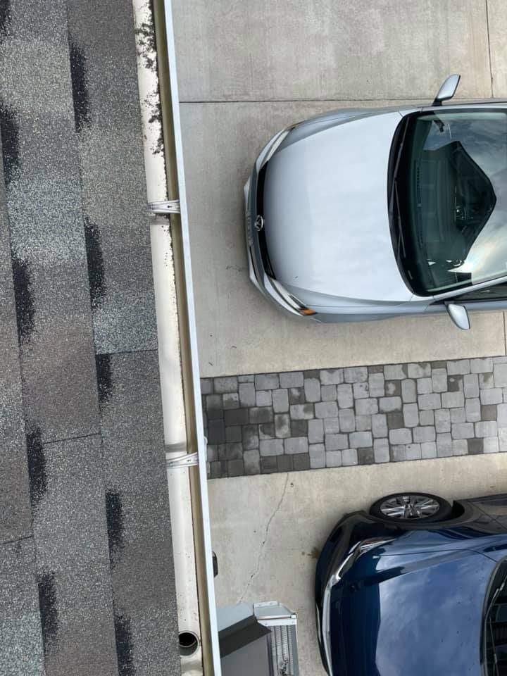 Parked silver and dark blue cars beside a curb and cobblestone walkway