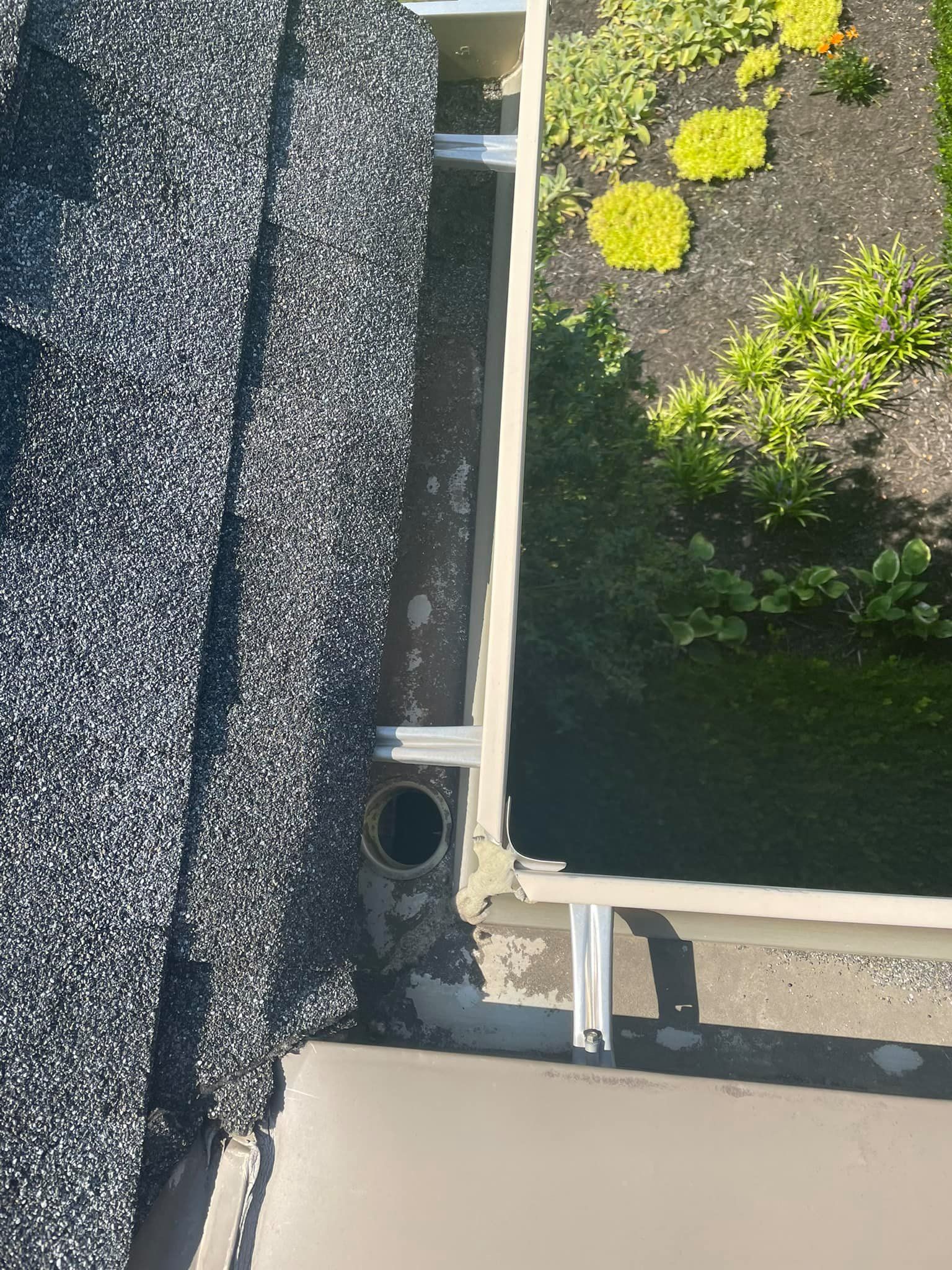 Rooftop edge with dark gravel, a beige ledge, and a small planted garden with yellow flowers