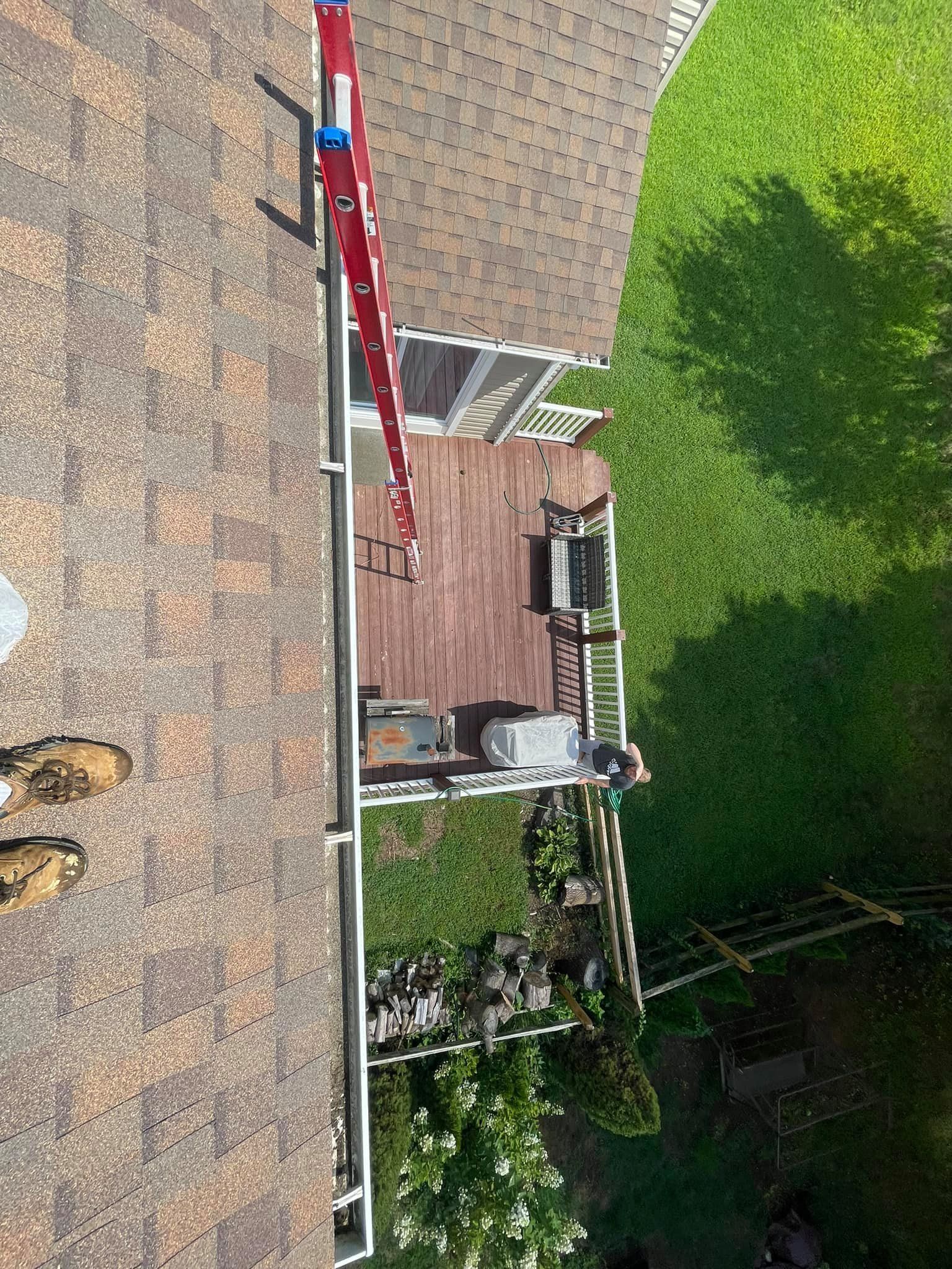 Backyard patio with brick house wall, red ladder, potted plants, and green lawn beyond.