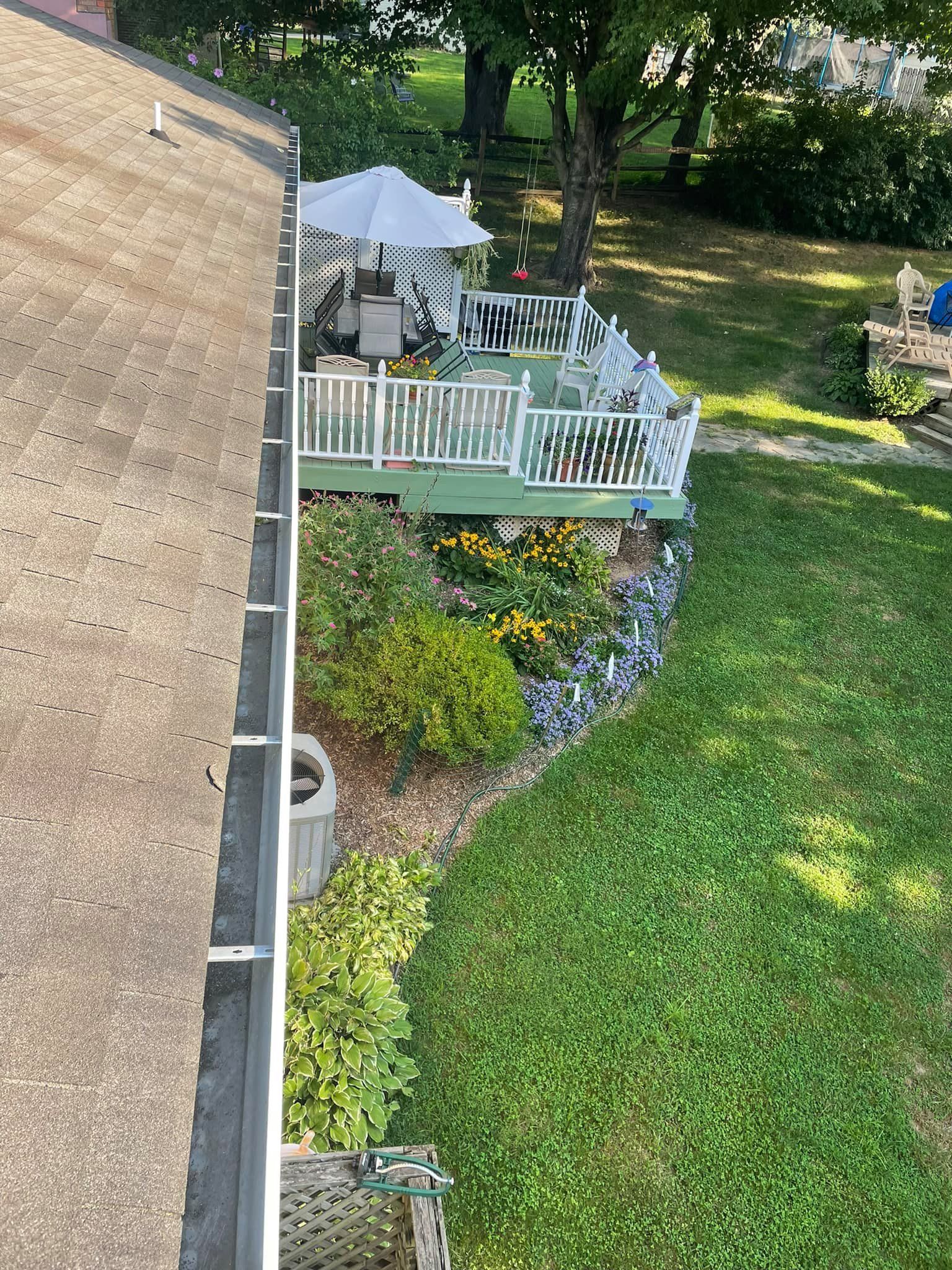 Backyard deck with white railing, patio umbrella, and green lawn beside a house.