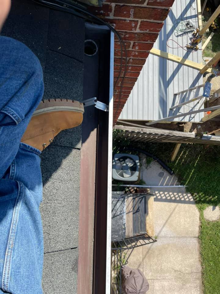 Person’s legs in jeans and brown boots on a black mat beside a balcony overlooking a fenced yard.