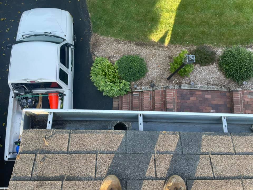 White pickup truck parked beside a brick driveway and green lawn, viewed from above.